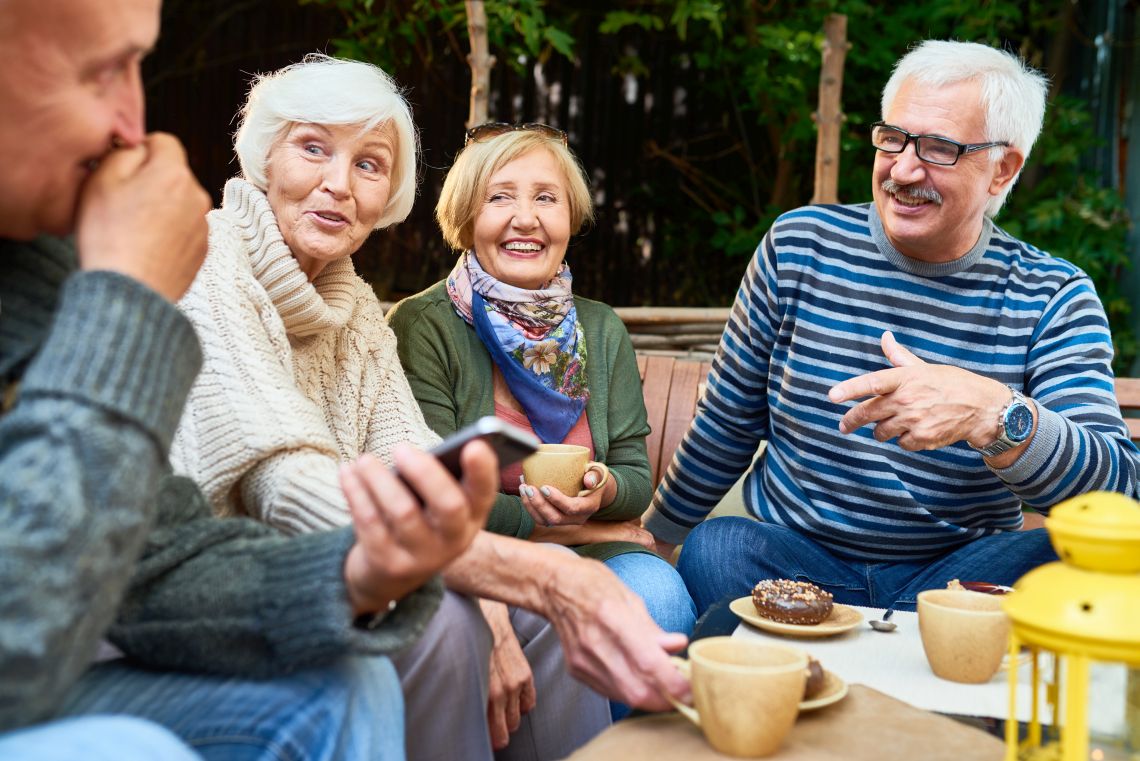 Vier ältere Menschen unterhalten sich bei Kaffee und Kuchen