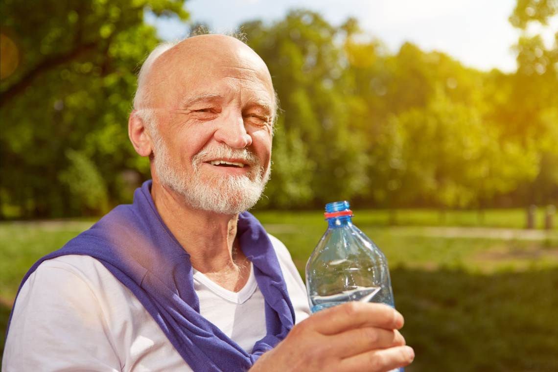 Wasser als Durstlöscher: Senior hält Wasserflasche in der Hand