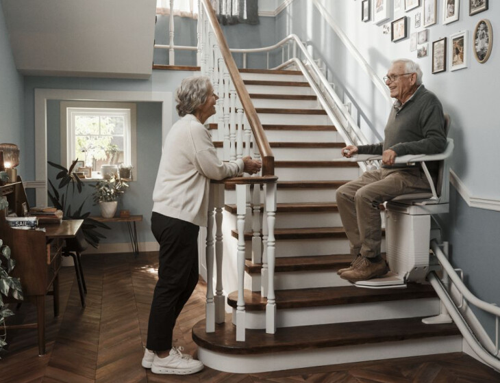 Ein Treppenlift befördert einen älteren Herren die Treppe nach unten