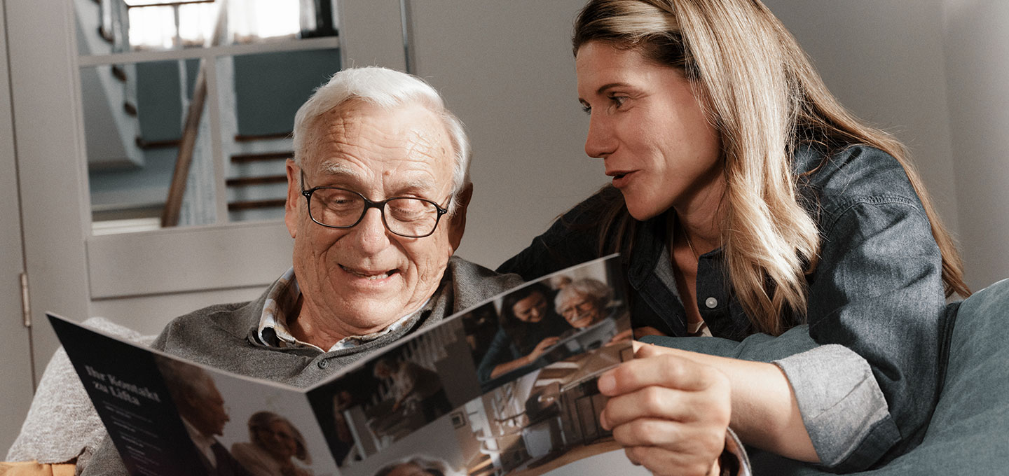 Vater und Tochter schauen Lifta Broschüre zu Treppenlift-Kosten an