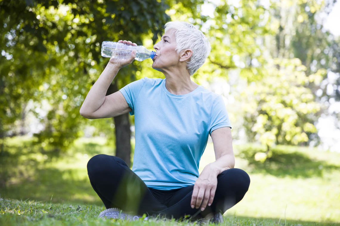 Sportlich gekleidete Frau trinkt Wasser