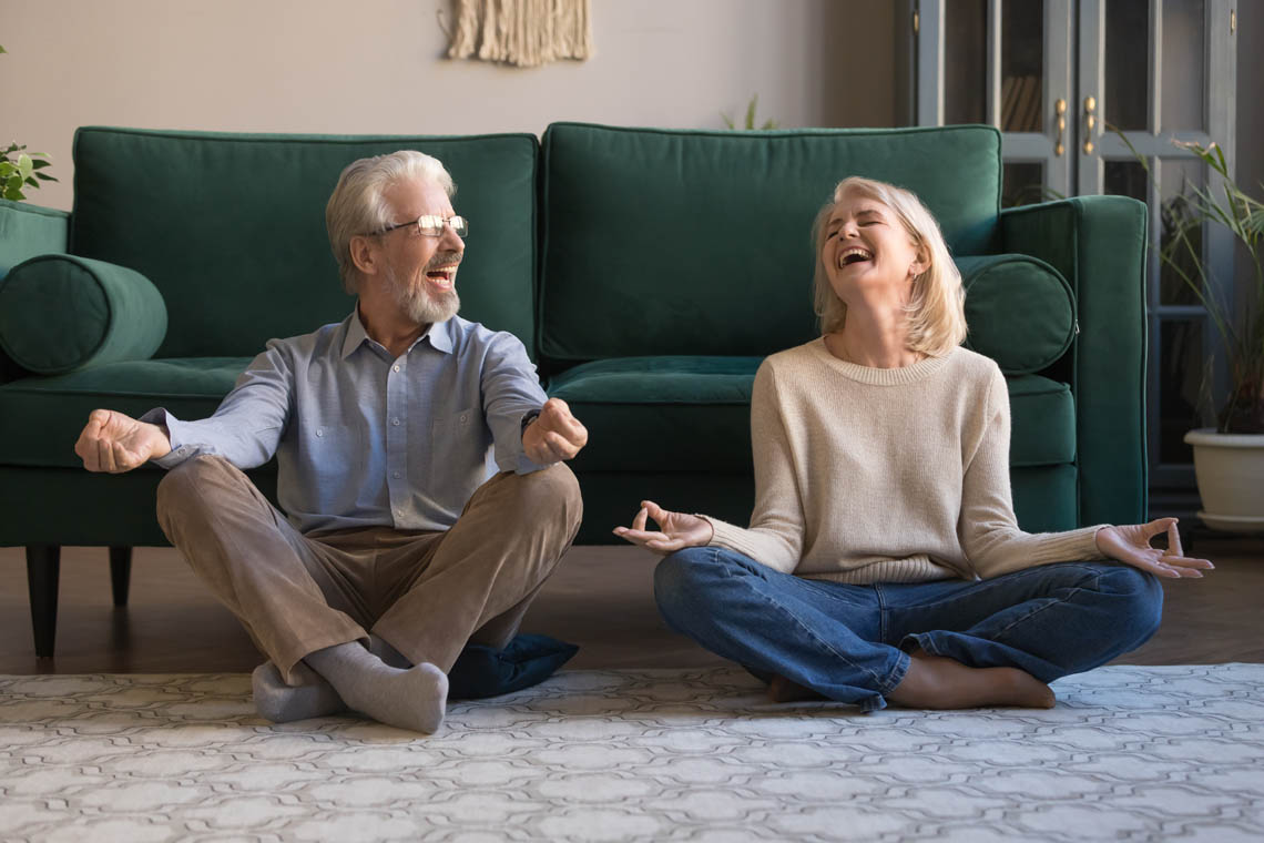 Älteres Paar lacht beim Meditieren