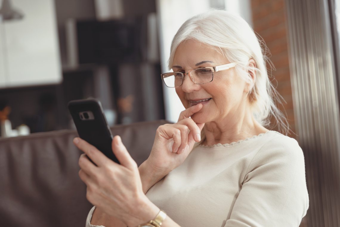 Frau schaut lächelnd auf ihr Handy