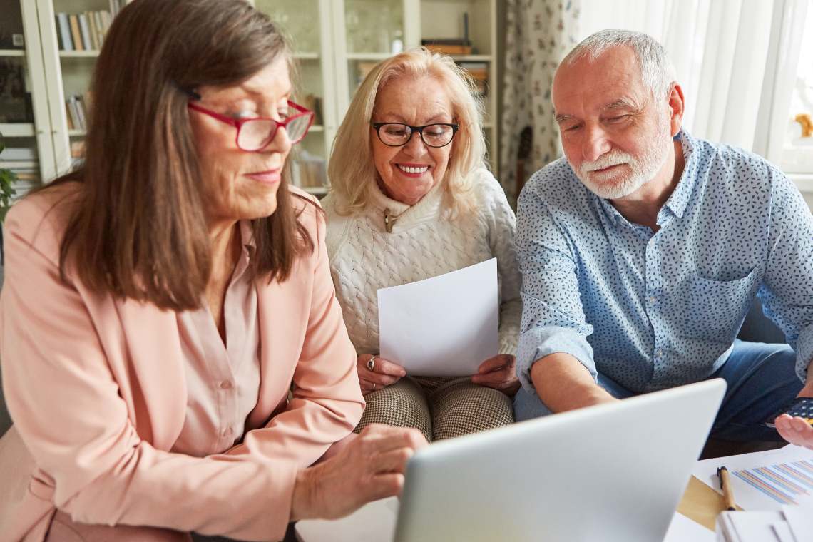 Drei Senioren informieren sich am Laptop über Fördermöglichkeiten für Barrierefreiheit