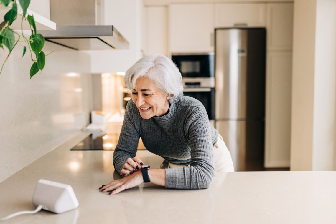 Frau steht in der Küche und steuert das Smart-Home-System über ihre Uhr
