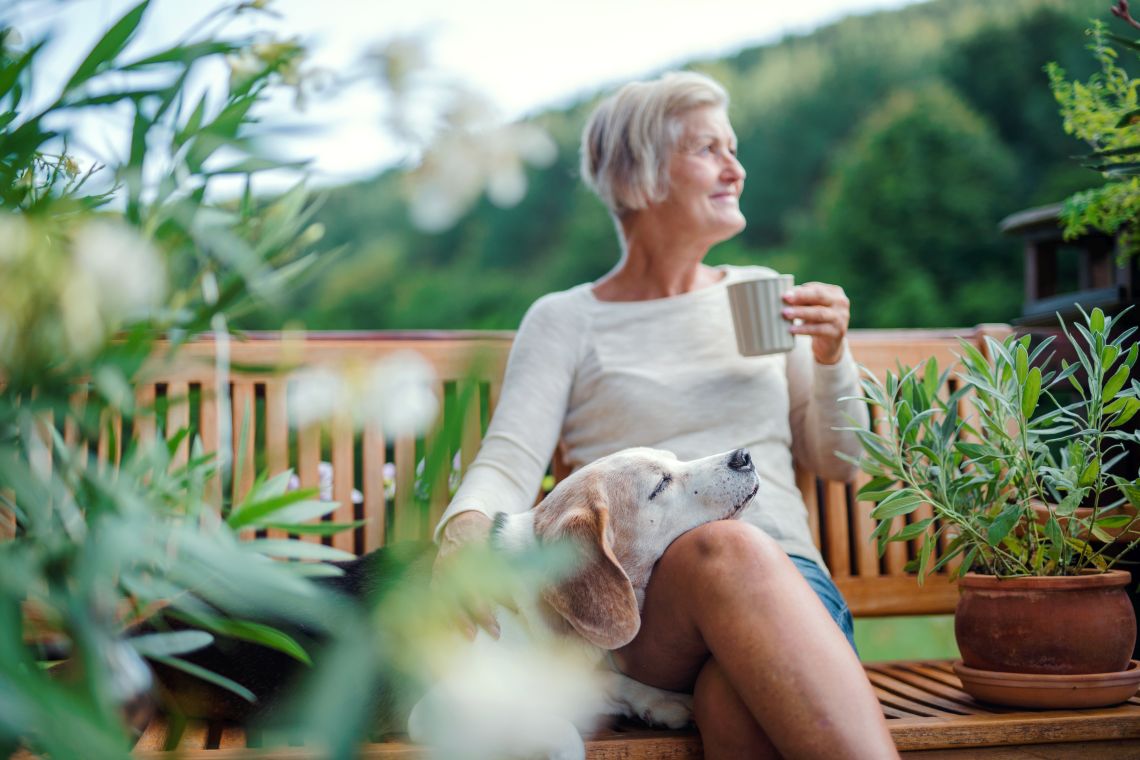 Frau entspannt auf einer Bank im barrierefreien Garten