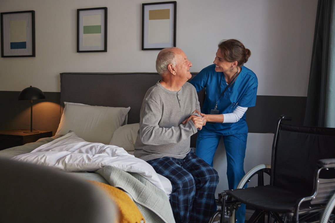 Eine Krankenpflegerin kümmert sich um einen bettlägerigen Patienten.