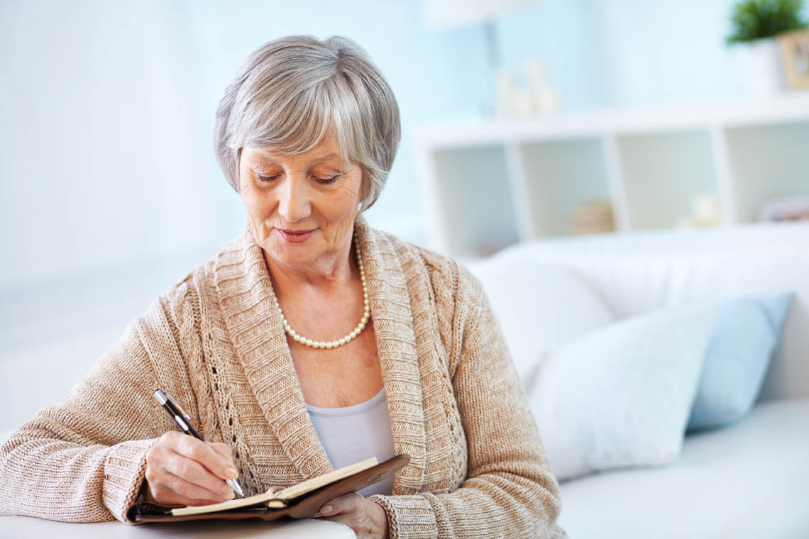 © © pressmaster | stock.adobe.com Seniorin schreibt etwas in ihr Notizbuch