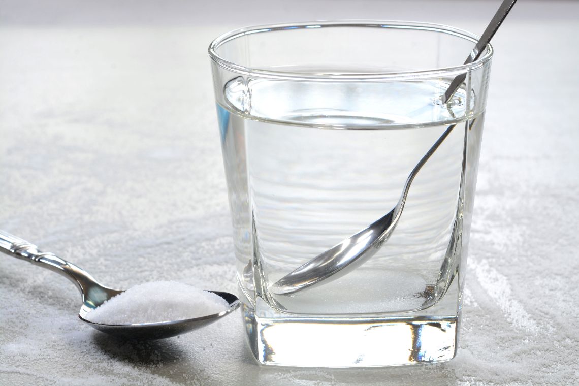 Glas Wasser mit einem Löffel Salz