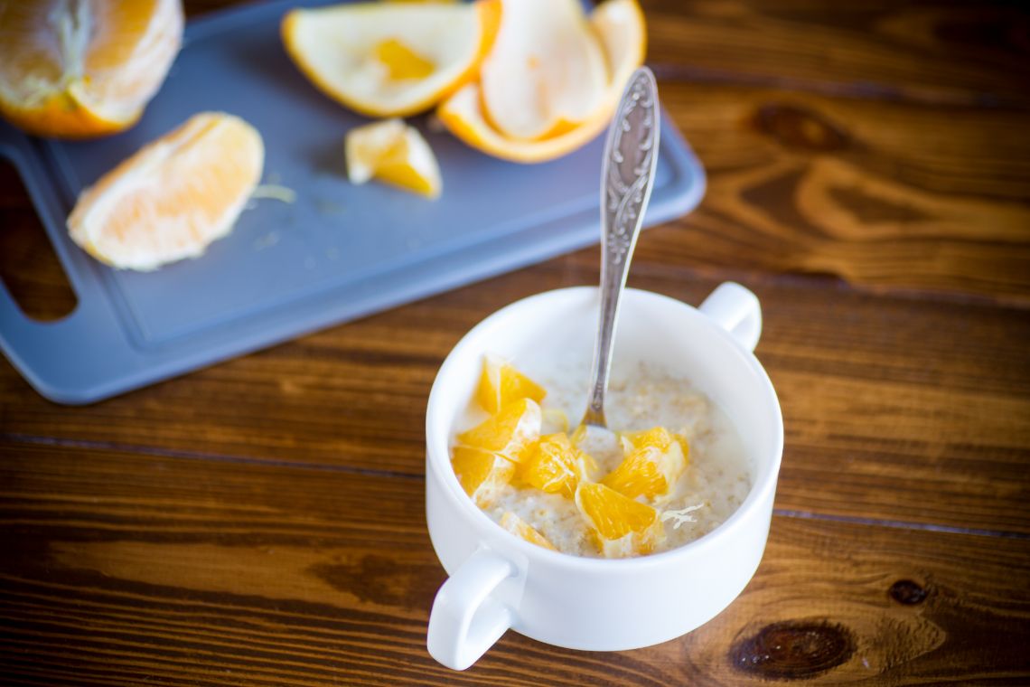 Tasse mit Haferbrei, Honig und Orangen