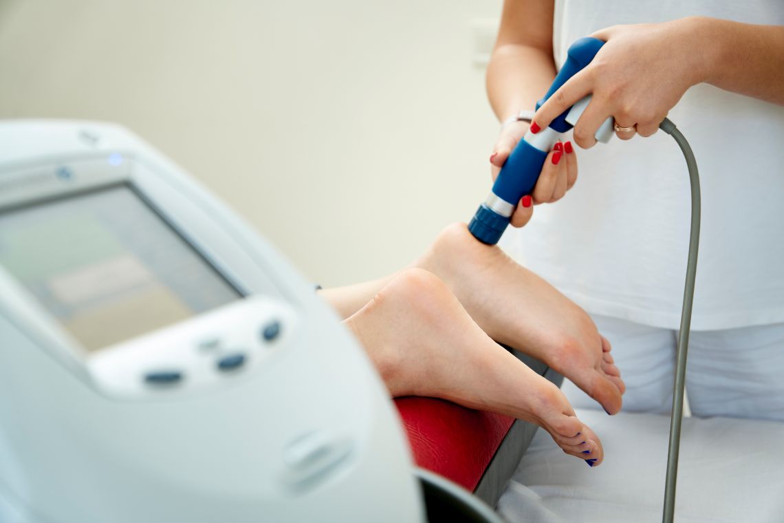 Durchführung einer Stoßwellentherapie zur Behandlung eines Fersensporns an der Ferse einer Patientin