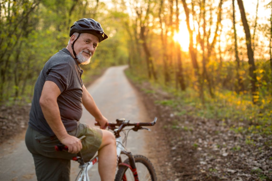 Senior fährt im Wald mit seinem Fahrrad