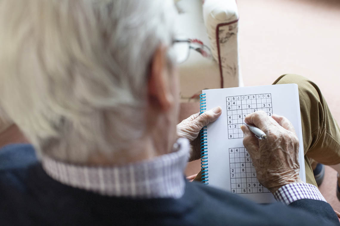 Älterer Mann löst Sudoku-Rätsel zu Hause