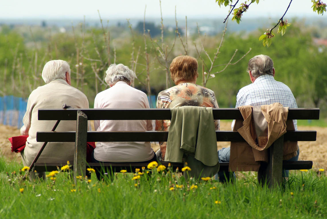 Vier Senioren sitzen auf einer Parkbank