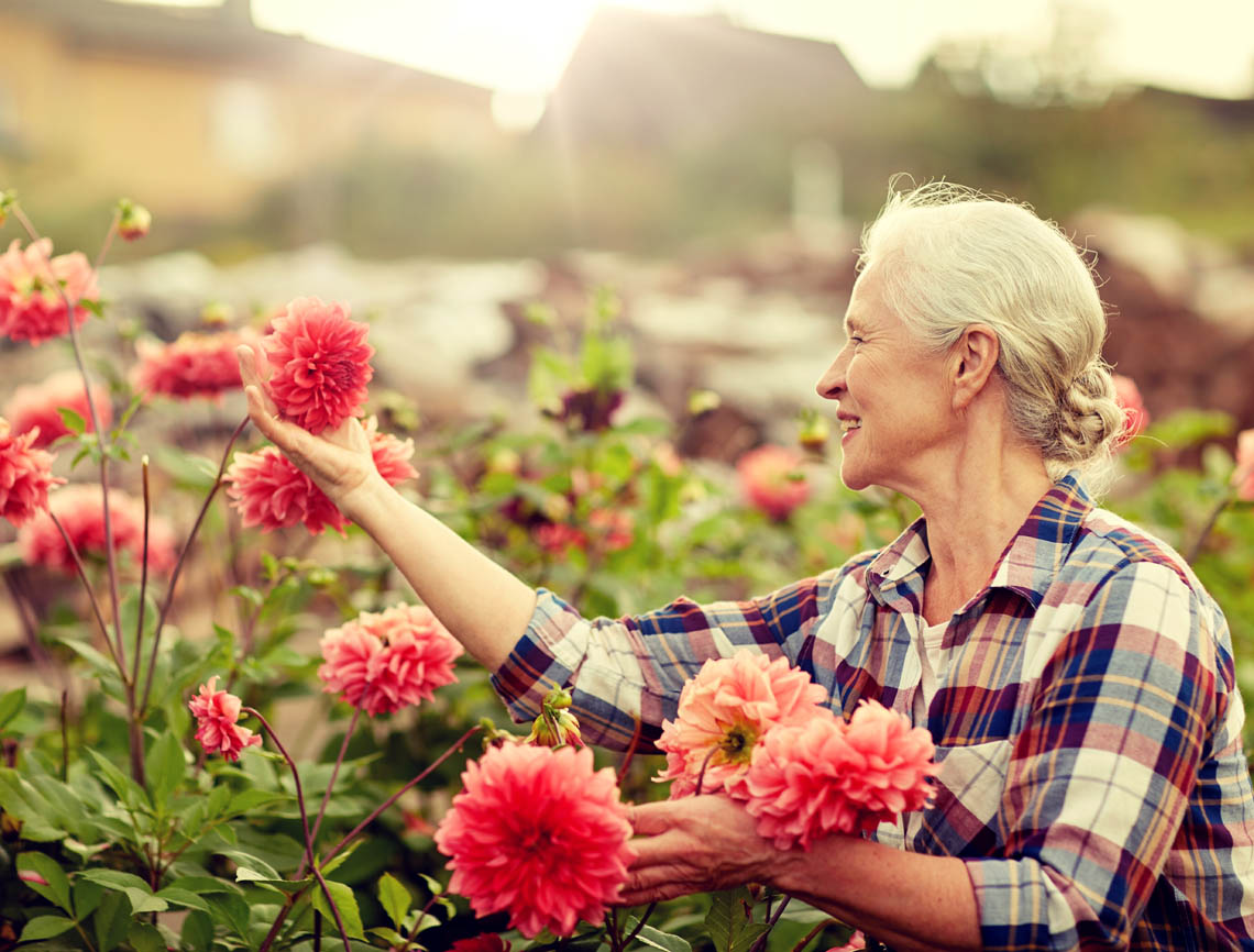 Seniorin lächelt Blume an