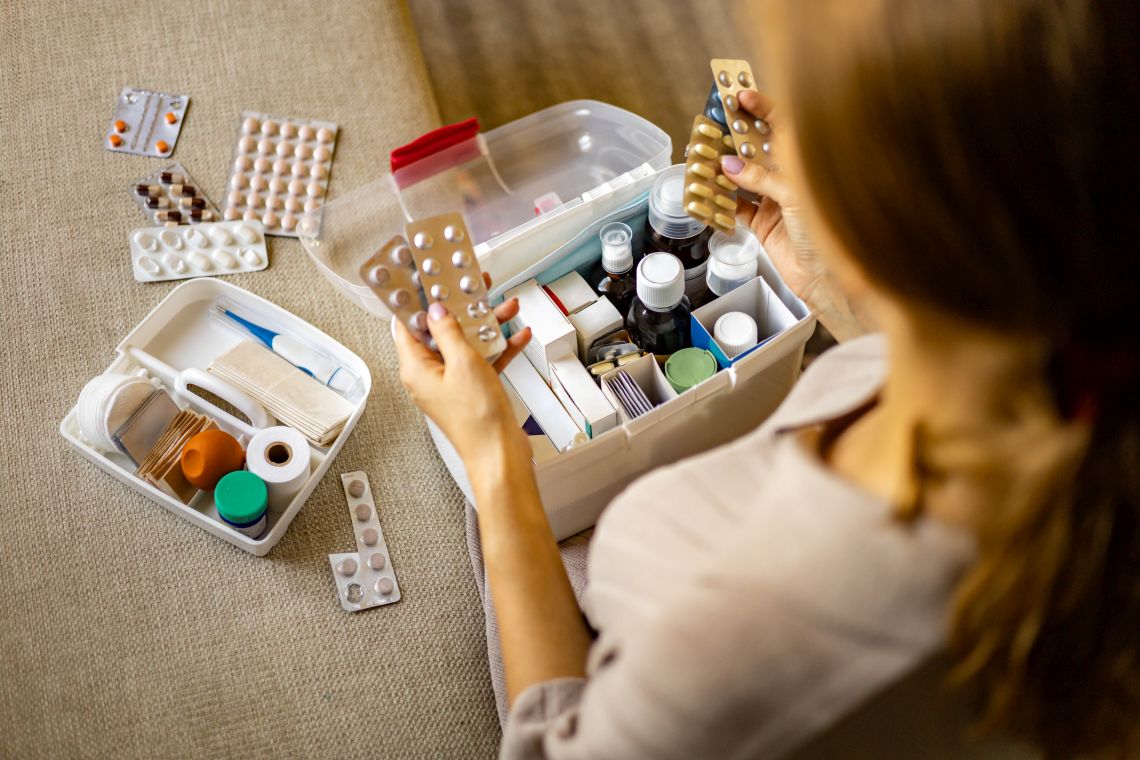 Frau sortiert Medikamente in ihrer Hausapotheke