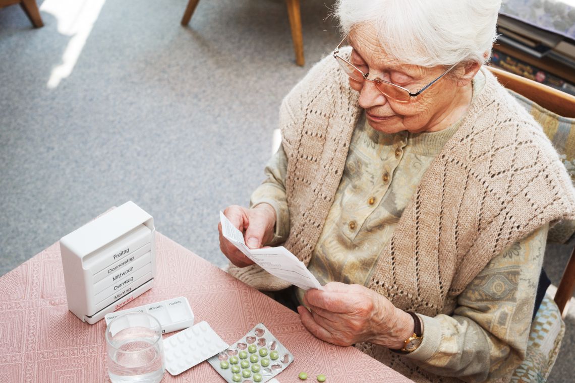 Ältere Dame liest Beipackzettel von Medikamenten der Hausapotheke