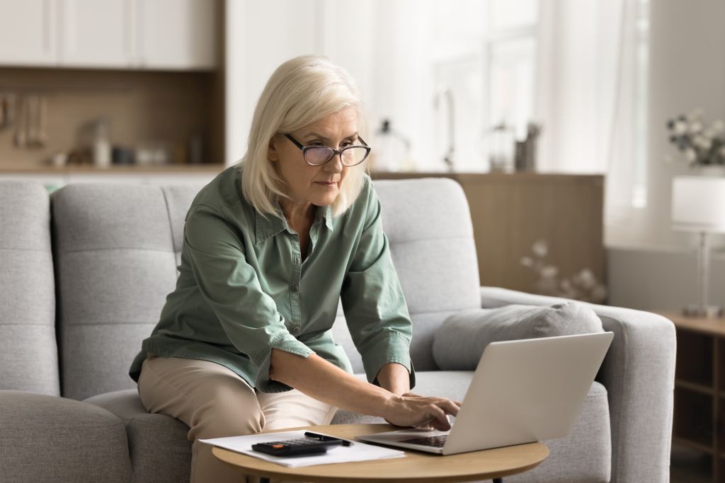 Eine Seniorin informiert sich am Laptop über die Finanzierungsmöglichkeiten von Haushaltshilfen