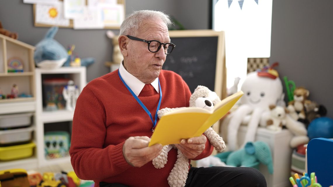 Rentner liest Kindern ein Buch vor