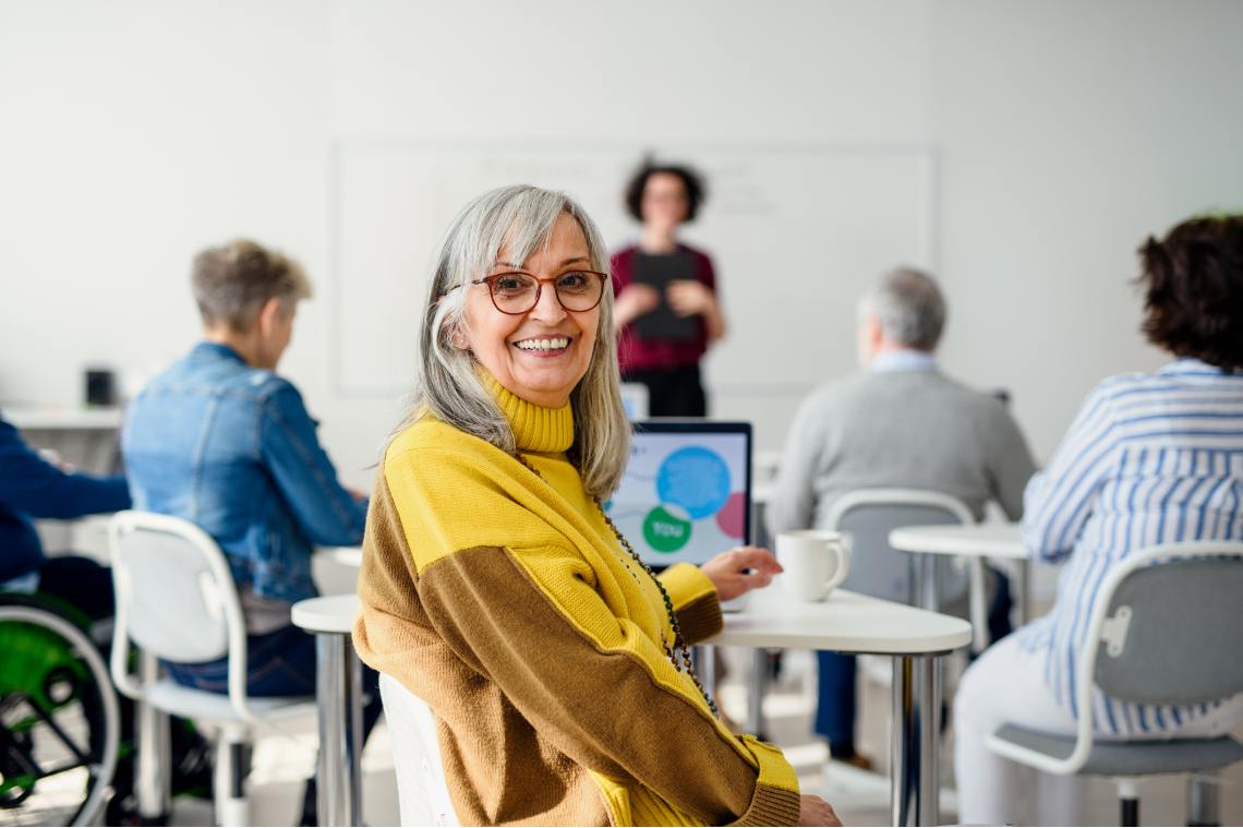 Lächelnde Frau vor ihrem Laptop im Computerkurs