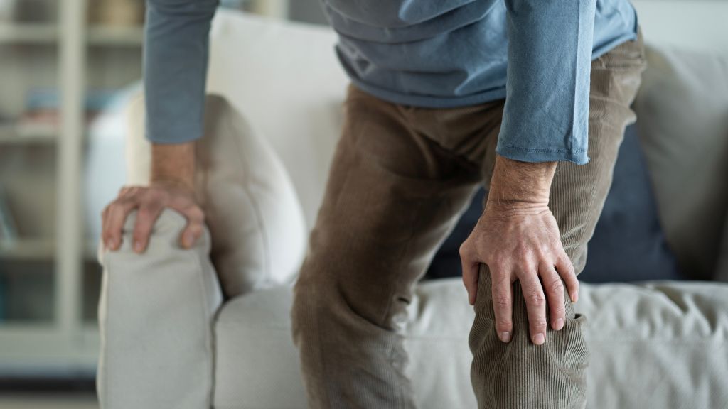 Ein Senior fasst sich vor Schmerzen ans Knie