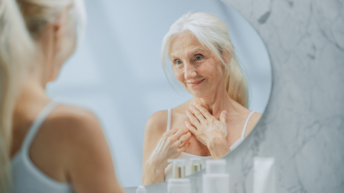 Körperliche Veränderungen im Alter: Seniorin blickt in Spiegel
