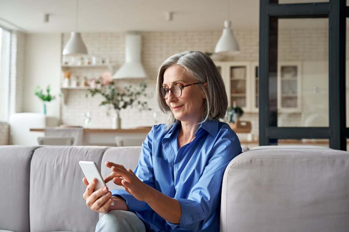 Frau sitzt auf dem Sofa und ist am Handy auf Partnersuche