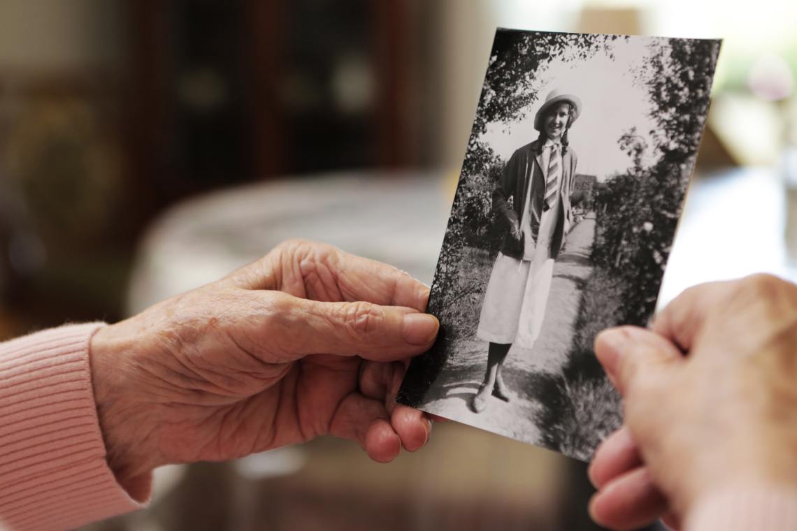 Seniorin hält ein schwarz-weiß Foto von sich in der Hand