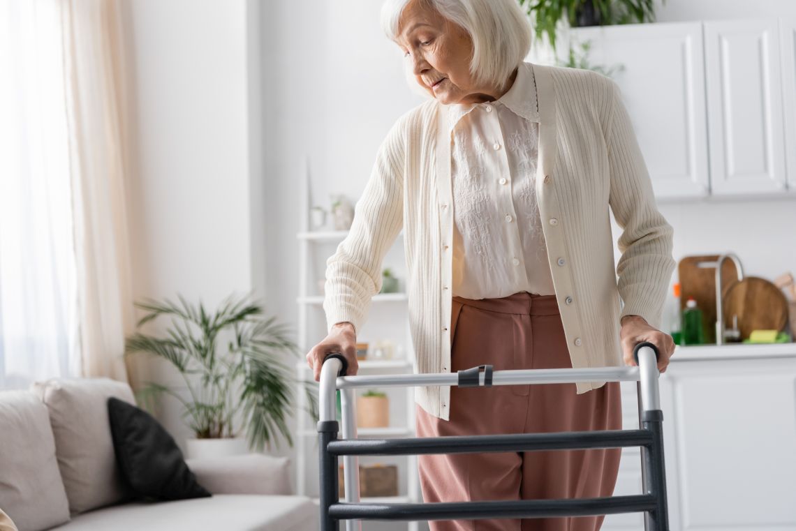 Eine Seniorin läuft mit einem Rollator durch ihre Wohnung