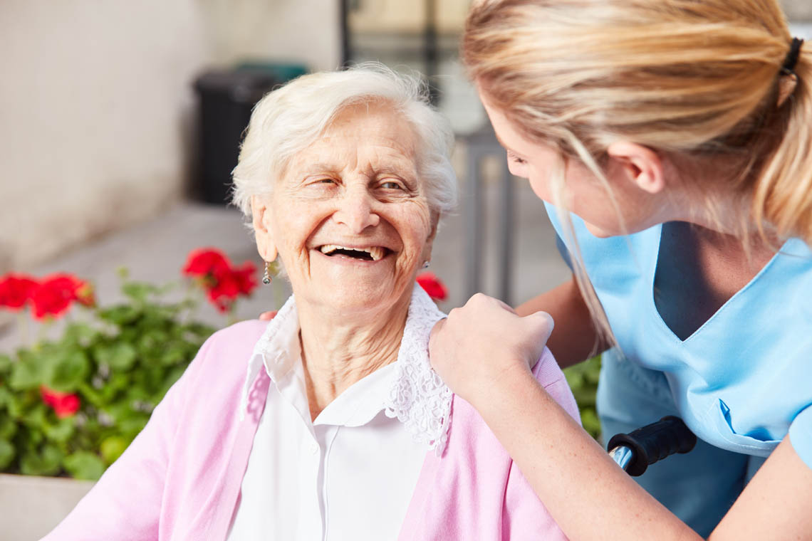 Seniorin lacht mit fürsorglicher Pflegerin