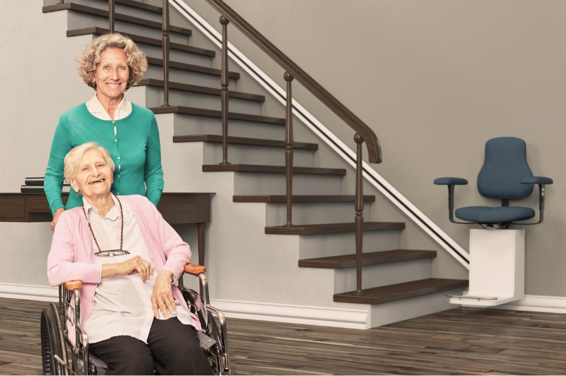Pflegestufen: Seniorin im Rollstuhl mit Pflegerin und Treppenlift