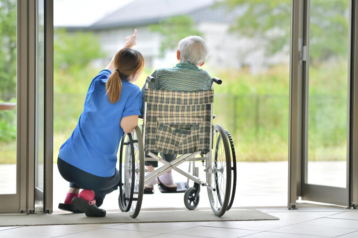Senior im Rollstuhl mit betreuender Pflegekraft