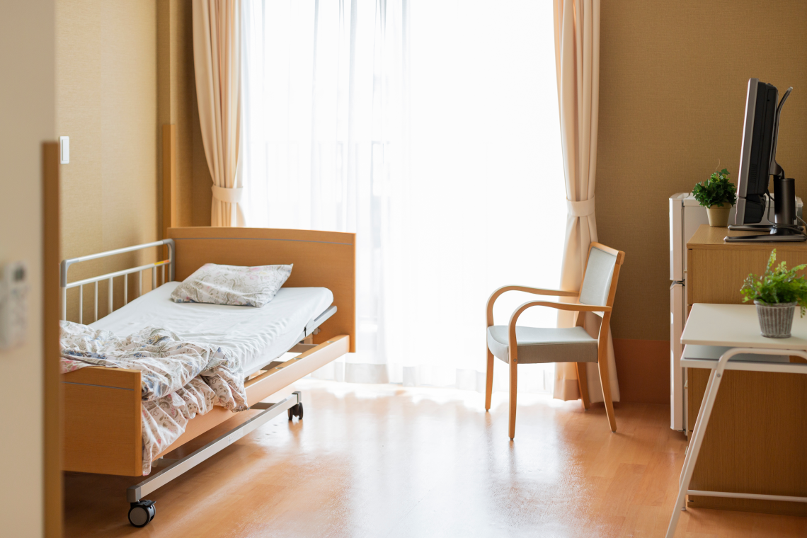 Pflegezimmer mit verstellbarem Pflegebett und Sitzgelegenheit