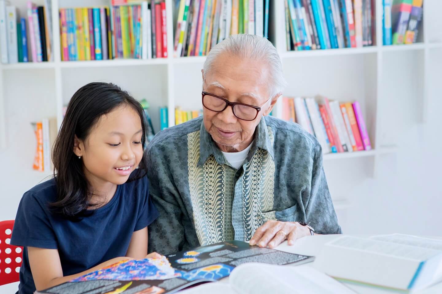 Rentner-Job: Älterer Herr hilft Kind beim Lesen