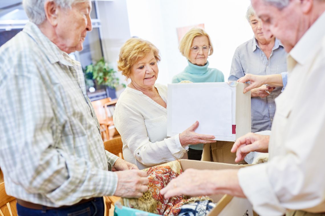 Eine gruppe Rentner sortiert Kleiderspenden in Boxen