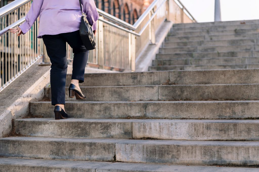 Eine ältere Dame mit Pumps geht eine Treppe mitten in der Stadt hoch