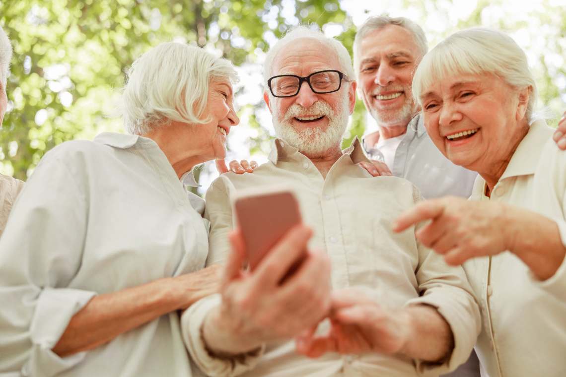 Gruppe Senioren schaut lachend auf ein Handy