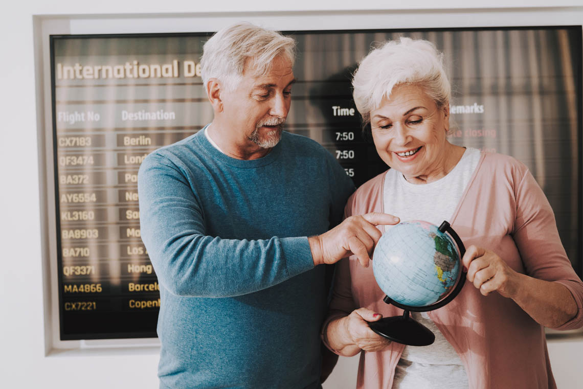 Älteres Paar mit Globus am Flughafen