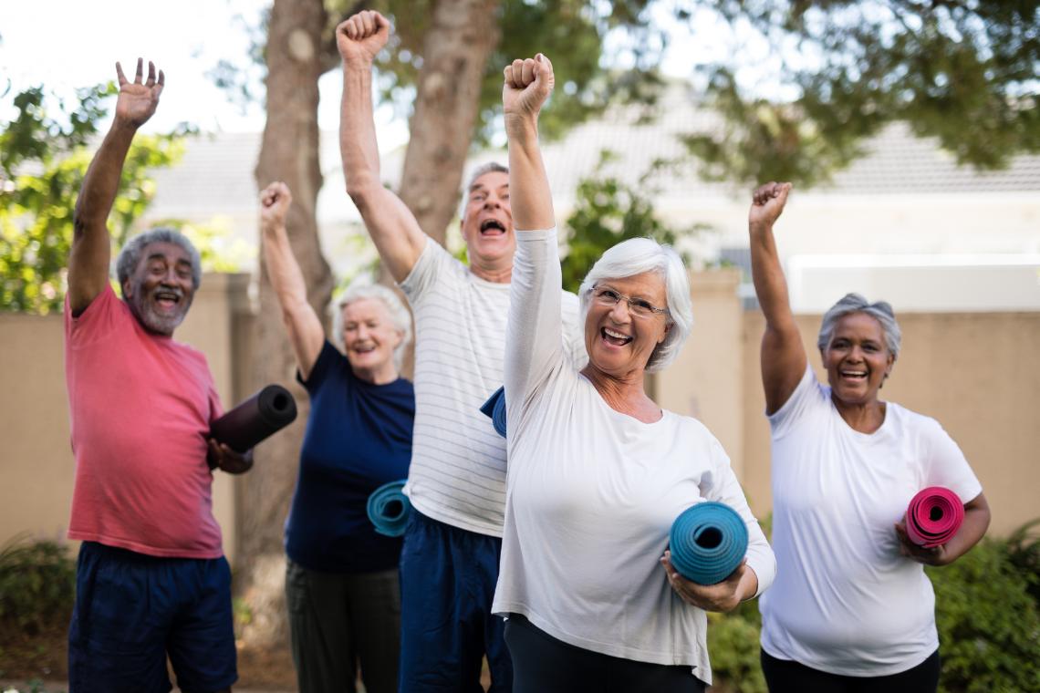 Senioren mit Yogamatten strecken Arm in die Luft