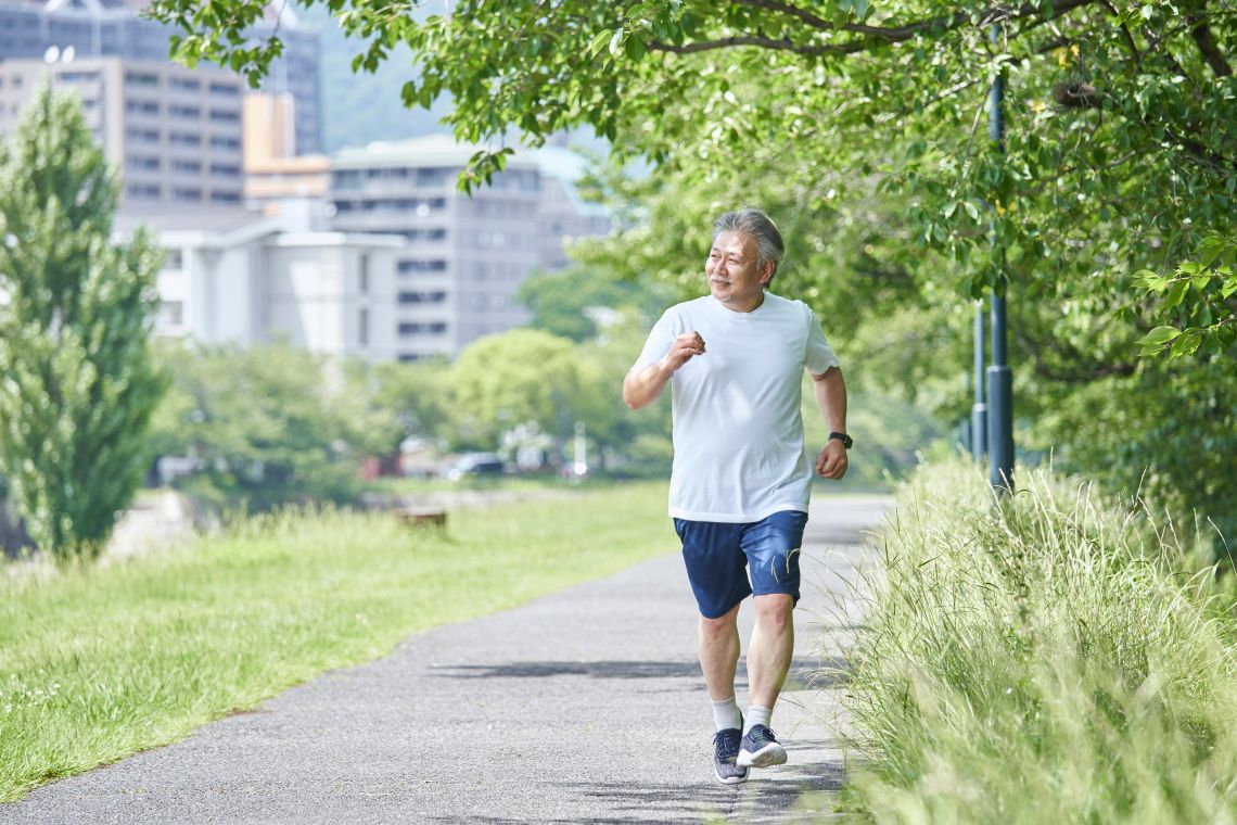 Ein älterer Mann joggt am Waldrand entlang
