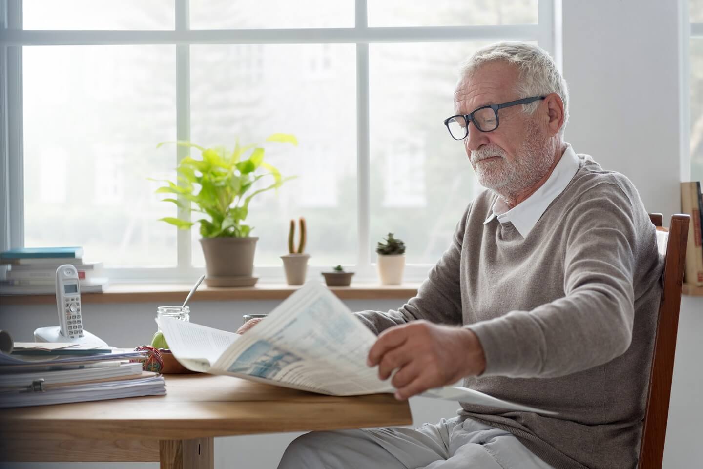 Rentner liest Zeitung am Tisch