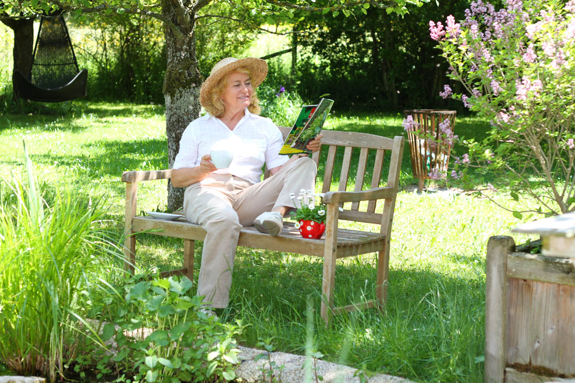 Frau entspannt und liest in ihrem Garten