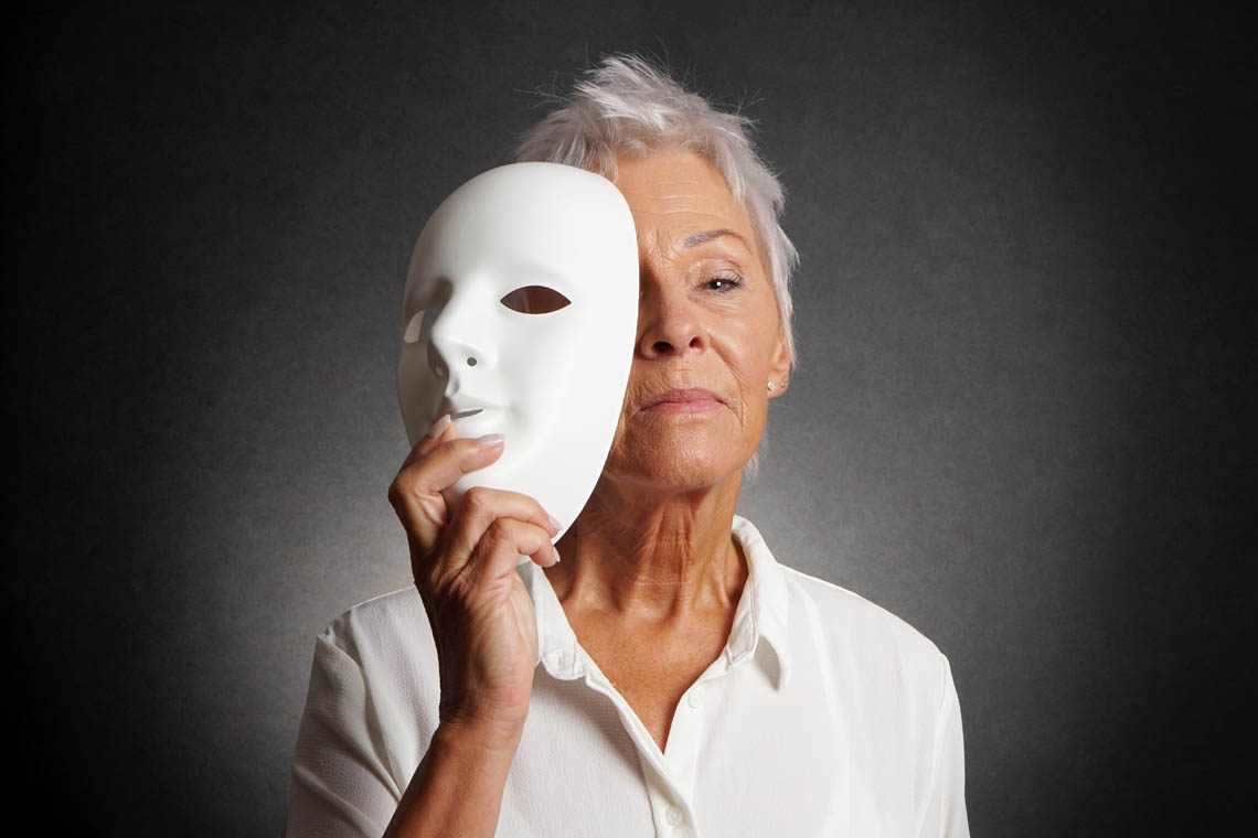 Theaterbegeisterte Seniorin hält Maske vor ihr Gesicht