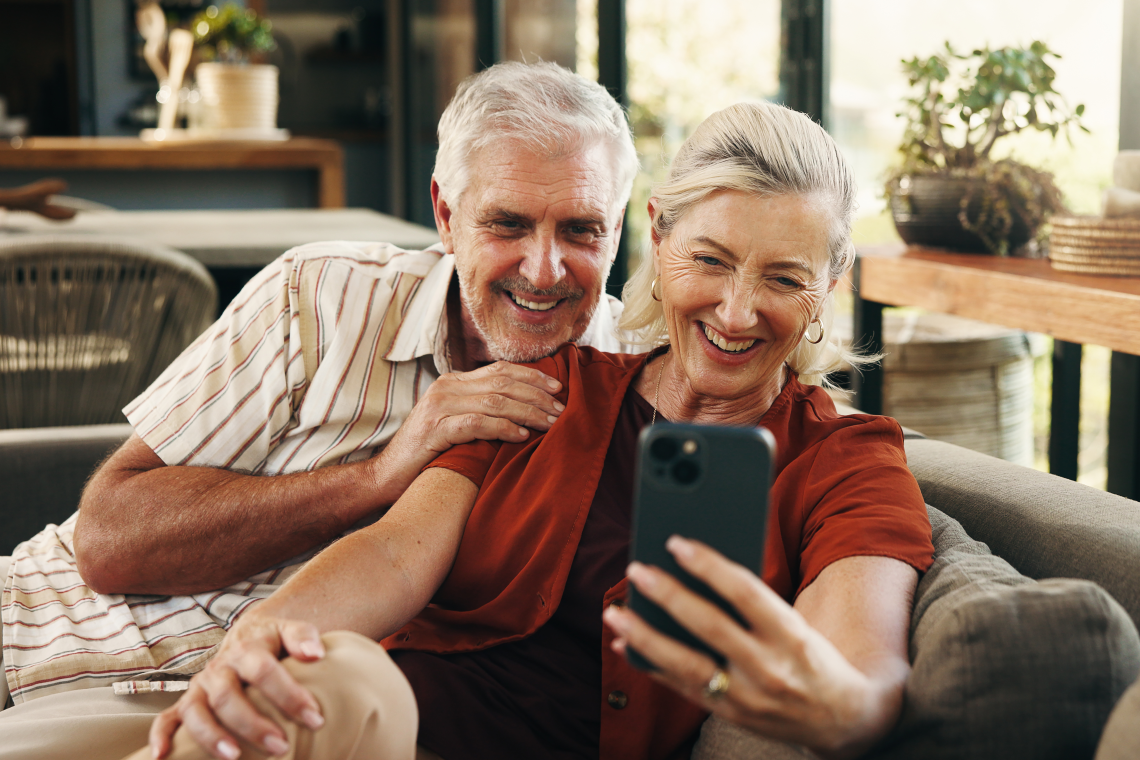 Älteres Paar lächelt beim Videochat via Smartphone