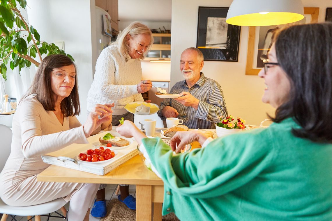 Eine Gruppe von vier Senioren isst gemeinsam am Tisch