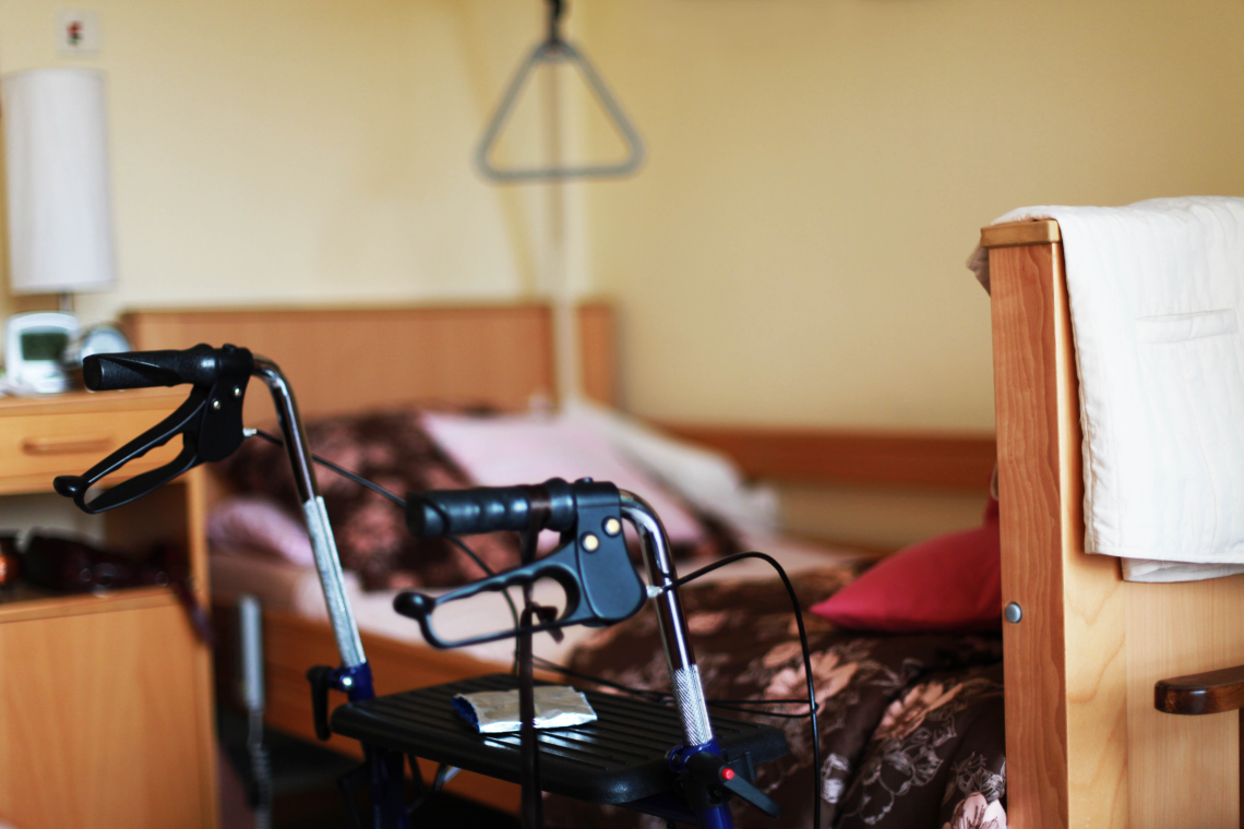 Rollator vor einem Pflegebett in einem hellen Schlafzimmer