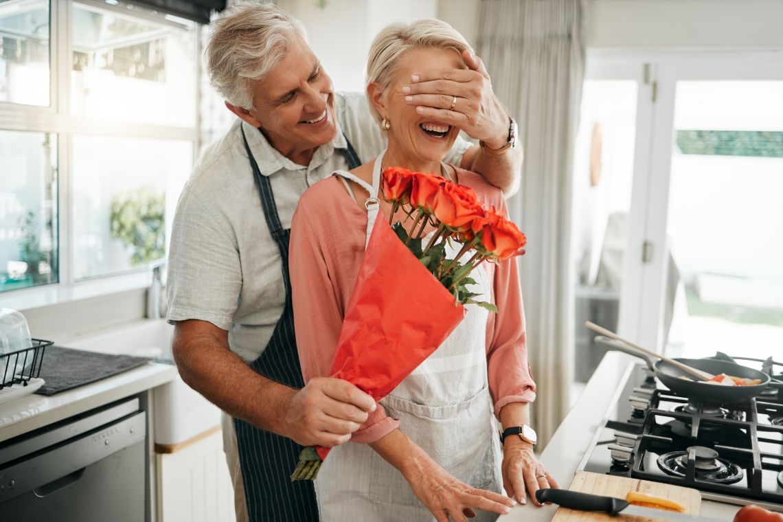 Älterer Mann überrascht Seniorin mit Rosen