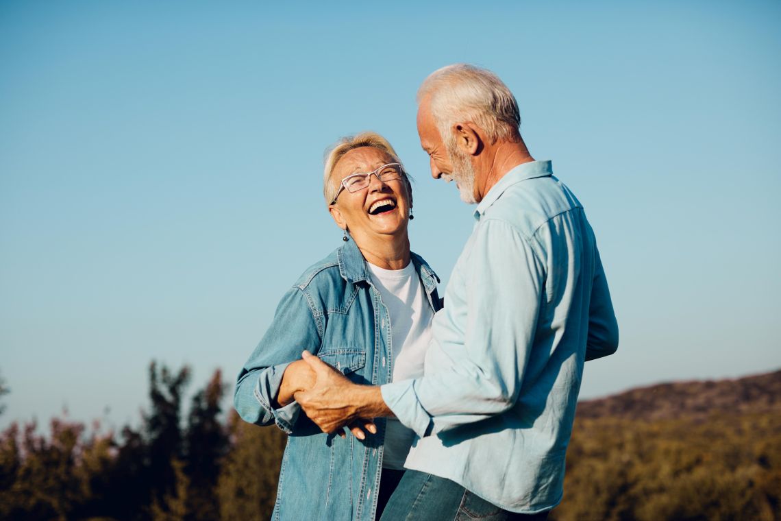 Ein älterer Mann und eine ältere Frau sind draußen gemeinsam glücklich