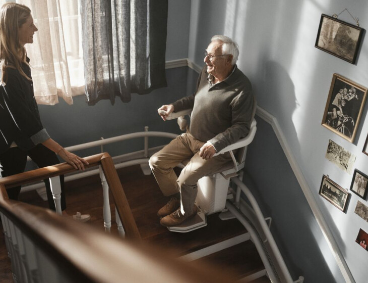 Mann fährt mit Sitzlift die Treppe hoch