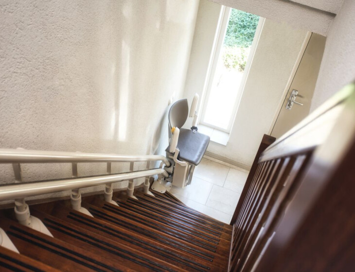 Ein Treppenlift parkt am Ende einer schmalen Holztreppe